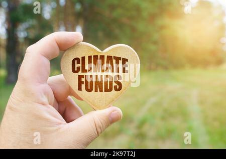 Concetto ecologico. Nelle mani di un uomo è una tavoletta sotto forma di un cuore su cui è scritto - Climate Funds Foto Stock
