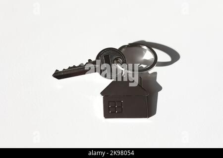 Portachiavi e portachiavi a forma di casa in metallo disposti su sfondo bianco con ombra. Commercio e assicurazione. Concetto di acquisto, vendita, locazione di vera esta Foto Stock