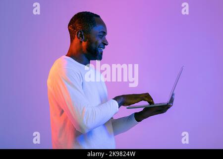 Felice uomo afroamericano che digita sulla tastiera del computer Foto Stock