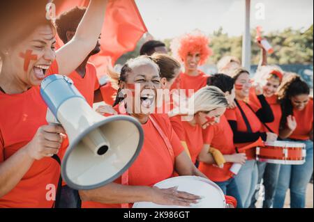 Il gruppo multirazziale di tifosi sportivi festeggia la vittoria della squadra Foto Stock