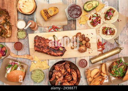 Set di deliziosi antipasti, tapas e costolette di pollo e maiale alla griglia, mais arrosto, salse, tacos di mais e guacamole Foto Stock