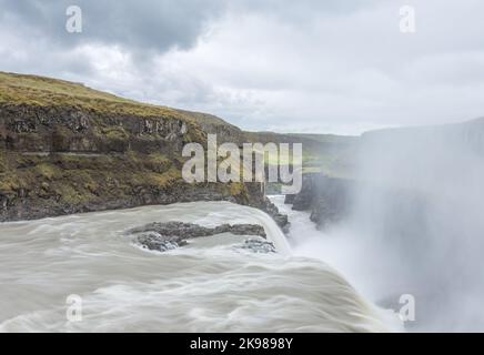 L'acqua tuona oltre il bordo della famosa cascata Gullfoss dell'Islanda, come nebbia e spruzzi sorgono dal burrone sottostante. Foto Stock