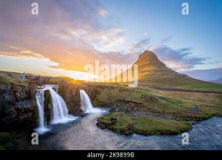 Tramonto estivo del sole di mezzanotte sulla famosa cascata di Kirkjufellfoss e sul monte Kirkjufell. Foto Stock