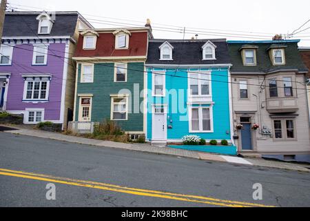 St. John's, Terranova, Canada-Ottobre 2022: Case a file di legno dai colori vivaci con un cielo blu sullo sfondo. Le case a tre piani sono colorate Foto Stock