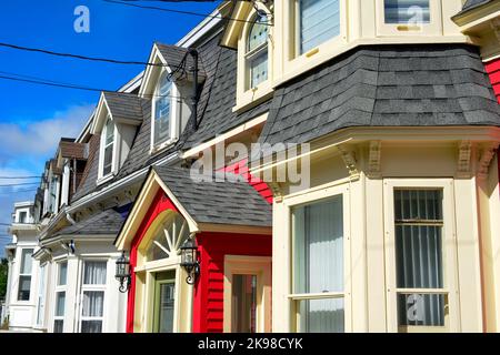 Case a file di legno dai colori vivaci con un cielo blu sullo sfondo. Le case a tre piani sono di colore giallo, rosso, blu e verde con case bianche Foto Stock