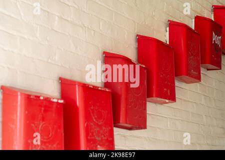 Più cassette postali, cassette postali o cassette postali in metallo rosso sono state fissate a una parete interna beige dell'edificio di appartamenti. Essi sono disposti in una cascata vicino Foto Stock