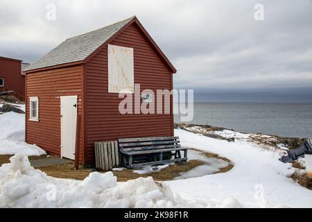 Un piccolo fienile rustico di colore rosso o capannone con una singola porta di legno bianca, una piccola finestra di vetro e una porta loft bianca sul bordo di un segno Cliff.Welcome Foto Stock