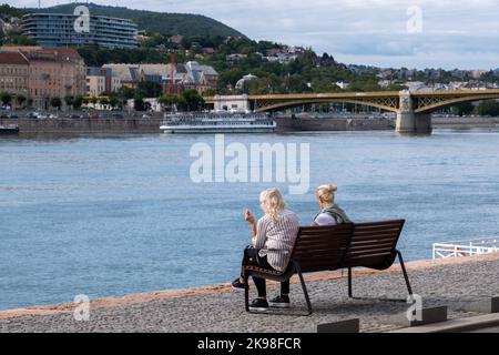 Budapest, Ungheria - 1st settembre 2022: Donne sedute su una panchina sulle rive del Danubio Foto Stock