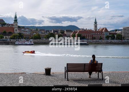 Budapest, Ungheria - 1st settembre 2022: Donna seduta su una panchina sulle rive del Danubio Foto Stock