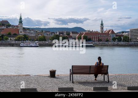 Budapest, Ungheria - 1st settembre 2022: Donna seduta su una panchina sulle rive del Danubio Foto Stock