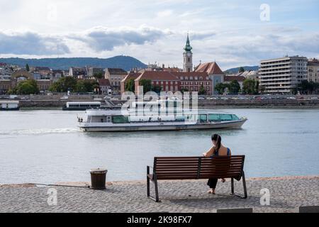 Budapest, Ungheria - 1st settembre 2022: Donna seduta su una panchina sulle rive del Danubio Foto Stock