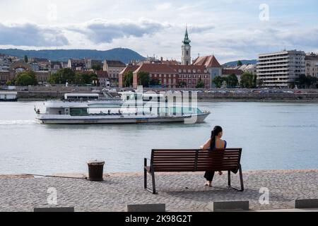 Budapest, Ungheria - 1st settembre 2022: Donna seduta su una panchina sulle rive del Danubio Foto Stock