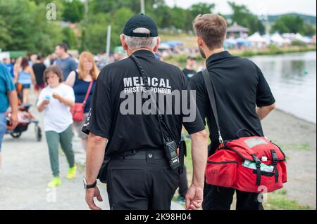 I soccorritori medici camminano lungo una strada che indossa uniformi nere, con il soccorritore medico in lettere grigie sul retro del paramedico. Foto Stock