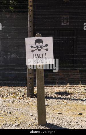 Stop segnale di avvertimento e recinzione elettrificata del filo spinato all'interno dell'ex campo di concentramento nazista di Auschwitz i, Auschwitz, Polonia. Foto Stock