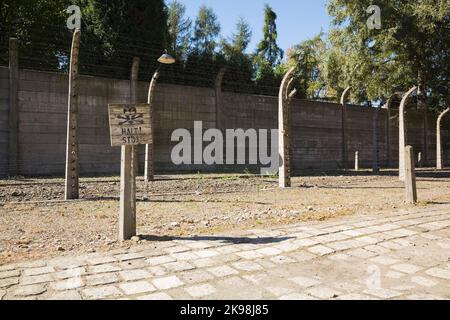 Stop segnale di avvertimento e recinzioni elettrificate di filo da fienile all'interno dell'ex campo di concentramento nazista di Auschwitz i, Auschwitz, Polonia. Foto Stock