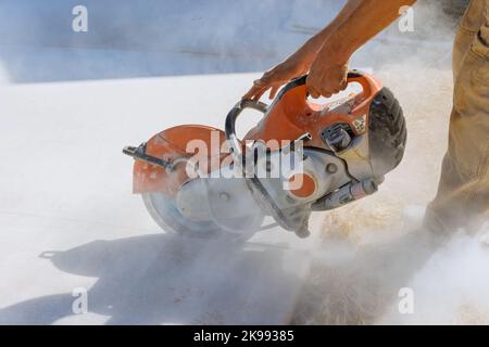 Taglio di lastre di pavimentazione in calcestruzzo per marciapiedi con taglio a lama diamantata Foto Stock