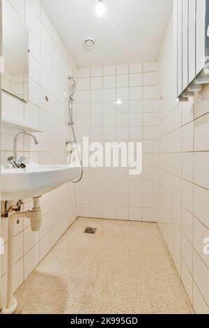 Interno della stanza della doccia con tubo e rubinetto sulle pareti del cemento del shabby ed il soffitto nel paese Foto Stock