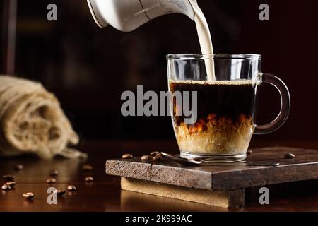 il latte viene versato sul caffè Foto Stock