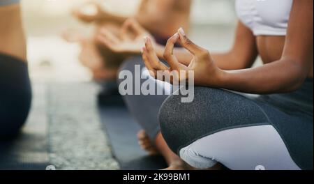 Siamo tutti in noi stessi: Un gruppo irriconoscibile di persone che si siedono e meditano insieme mentre si trovano in spiaggia durante una giornata di lavoro. Foto Stock