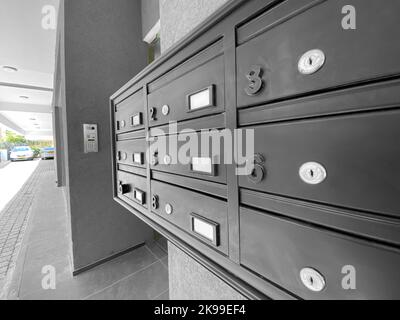 Vista in primo piano delle moderne cassette postali sulle pareti grigie dell'edificio residenziale Foto Stock