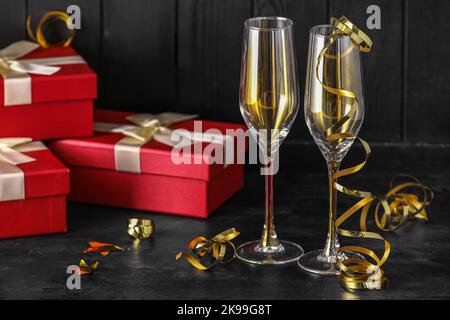 Calici a serpentina e regali di Natale su sfondo di legno scuro Foto Stock