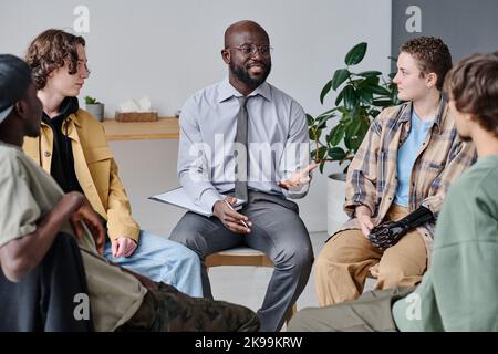 Psicoterapeuta africana che parla ai giovani durante la sessione in classe Foto Stock