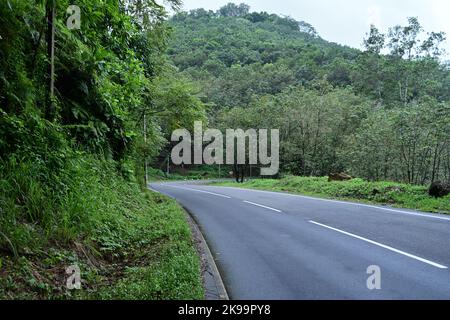 Vista su strada di una ripida strada di montagna nelle giornate piovose con una svolta brusca in avanti in Sri Lanka Foto Stock