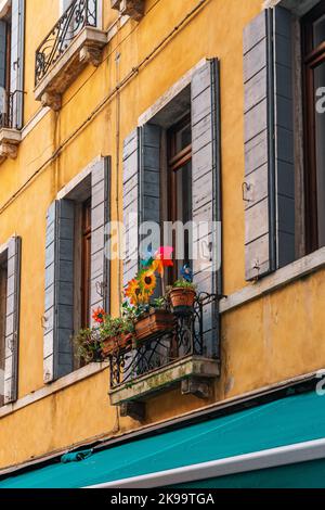 Una bella foto di fiori colorati su un balcone di un edificio giallo Foto Stock
