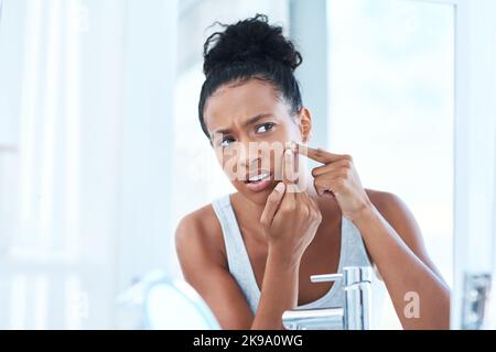 Come è successo questo. Una bella giovane donna che ha schiacciato un pimple nello specchio. Foto Stock