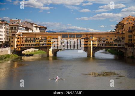 Ponte ad arco, il Ponte Vecchio a Firenze, case riflesse in acqua fluente in primo piano una barca a remi, uno sci Foto Stock