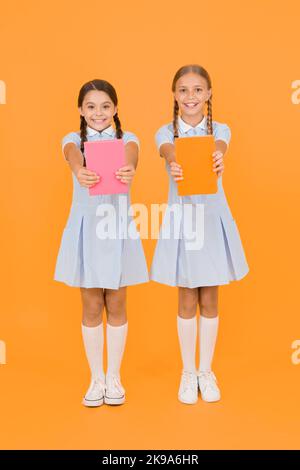 Biblioteca scolastica. Concetto di homeschooling. Centro di alfabetizzazione. Bambini carini che tengono libri su sfondo giallo. Bambine con enciclopedia o bambini Foto Stock