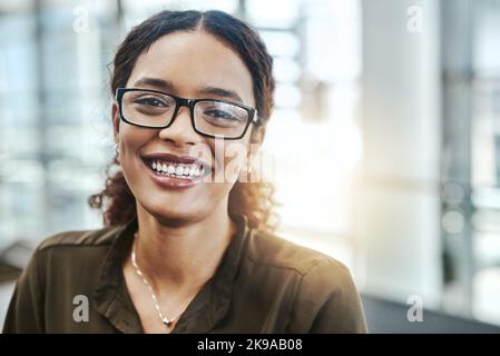 Tutto paga bene alla fine. Ritratto corto di una giovane donna d'affari attraente sorridente mentre si trova in un ufficio moderno. Foto Stock