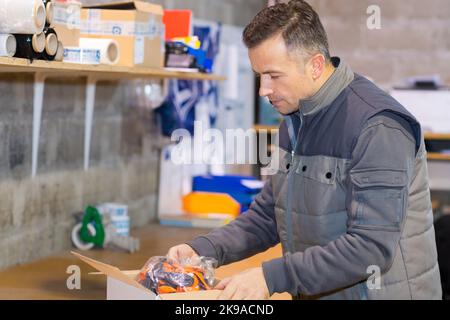 operatore che mette le parti meccaniche in una scatola Foto Stock