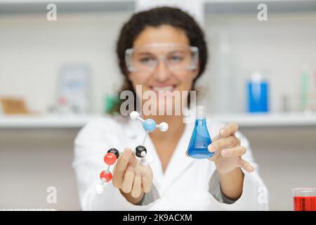 scienziato femminile che detiene atomi modello e fiasca di vetro Foto Stock