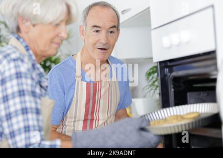 felice marito e donna che tiene vassoio con biscotti Foto Stock