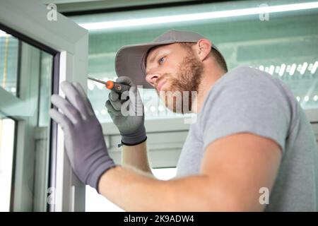 contractor maschio utilizzando un cacciavite sulla finestra in pvc Foto Stock