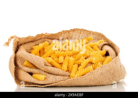 Pasta di grano duro in sacchetto di iuta, macro, isolata su fondo bianco. Foto Stock