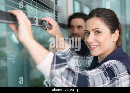 donna felice che installa tende con cacciavite Foto Stock