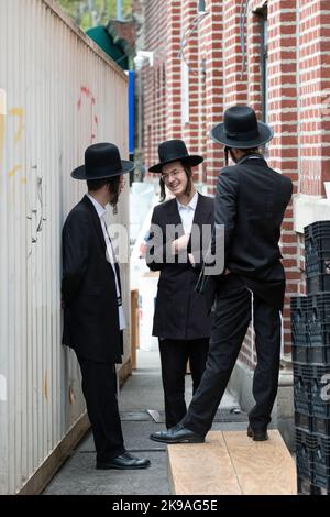 3 uomini ebrei ortodossi socializzano e ridono dopo i servizi mattutini in una sinagoga Vien a Brooklyn, New York. Foto Stock