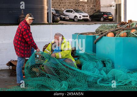 26 ottobre 2022. Fraserburgh, Aberdeenshire, Scozia. Si tratta di due uomini nel processo di riparazione di una grande rete da pesca sul molo di Fraserburgh Harb Foto Stock