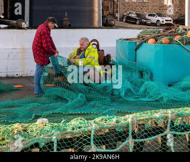 26 ottobre 2022. Fraserburgh, Aberdeenshire, Scozia. Si tratta di due uomini nel processo di riparazione di una grande rete da pesca sul molo di Fraserburgh Harb Foto Stock