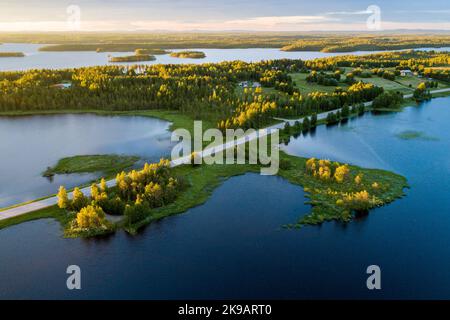 Strada nel mezzo del paesaggio del lago durante un bellissimo tramonto estivo nella Finlandia settentrionale Foto Stock