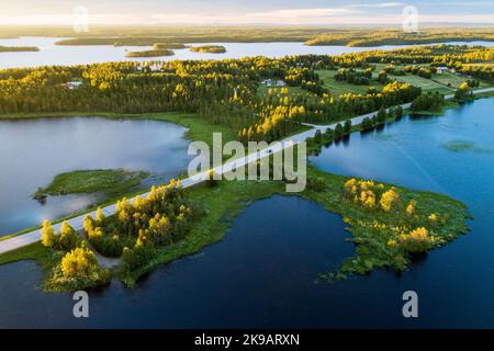 Strada nel mezzo del paesaggio del lago durante un bellissimo tramonto estivo nella Finlandia settentrionale Foto Stock