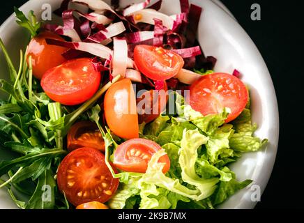 Insalata mista con lattuga, pomodoro e foglie di rucola fresca. Piatto vegetariano. Foto Stock