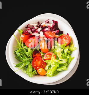 Insalata mista con lattuga, pomodoro e foglie di rucola fresca. Piatto vegetariano. Foto Stock