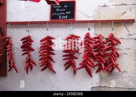 Peperoni rossi in grappoli appesi su un muro bianco durante l'annuale festa del pepe di Espelette in Francia Foto Stock