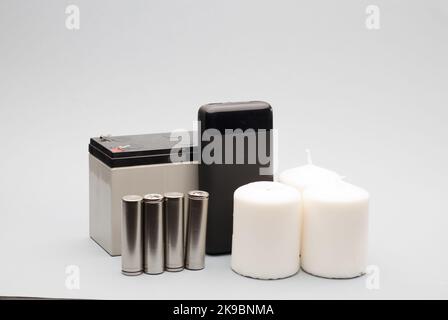 apparecchiature di emergenza, power bank con batterie, candele bianche e sfondo grigio della batteria Foto Stock