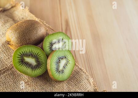 Frutta kiwi su sfondo di legno. Intero e pezzi. Spazio di copia Foto Stock