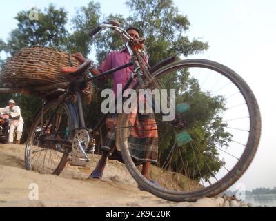 Naogaon, Bangaldesh. 27th Ott 2022. Un venditore spinge la sua bicicletta mentre attraversa il fiume Atria durante il tramonto nella periferia del cappello di Dhamoir del distretto di Naogaon. (Credit Image: © MD Mehedi Hasan/ZUMA Press Wire) Credit: ZUMA Press, Inc./Alamy Live News Foto Stock