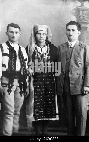 Copia di una foto B&N dei primi anni del 20th° secolo raffigurante una famiglia di rumeni della contea di Gorj, nella regione di Oltenia. Due delle persone indossano abiti tradizionali locali, mentre l'altra si trova nell'abbigliamento della 'città'. Foto Stock